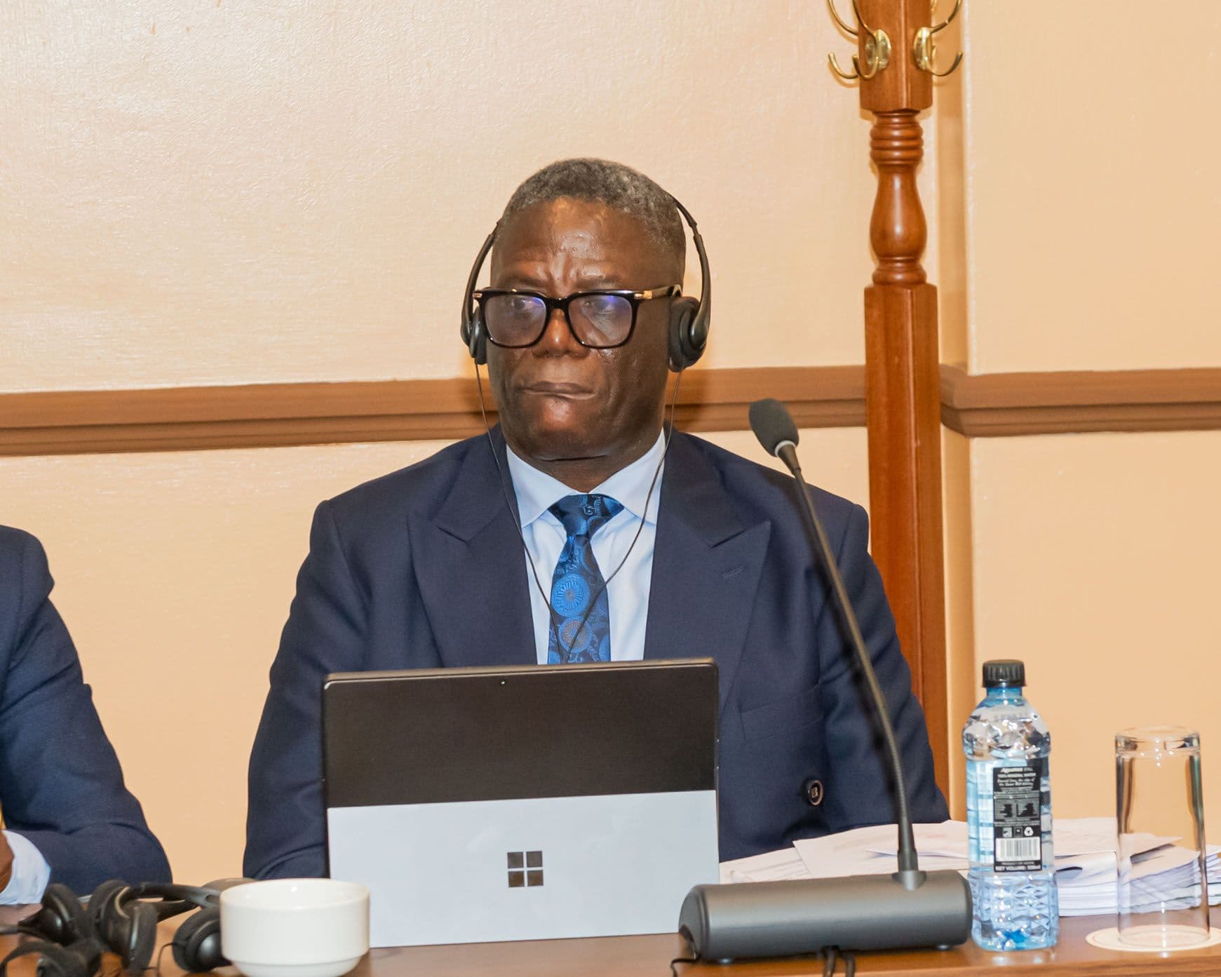 A delegate follows the session on a tablet, microphone and interpretation headset in place.