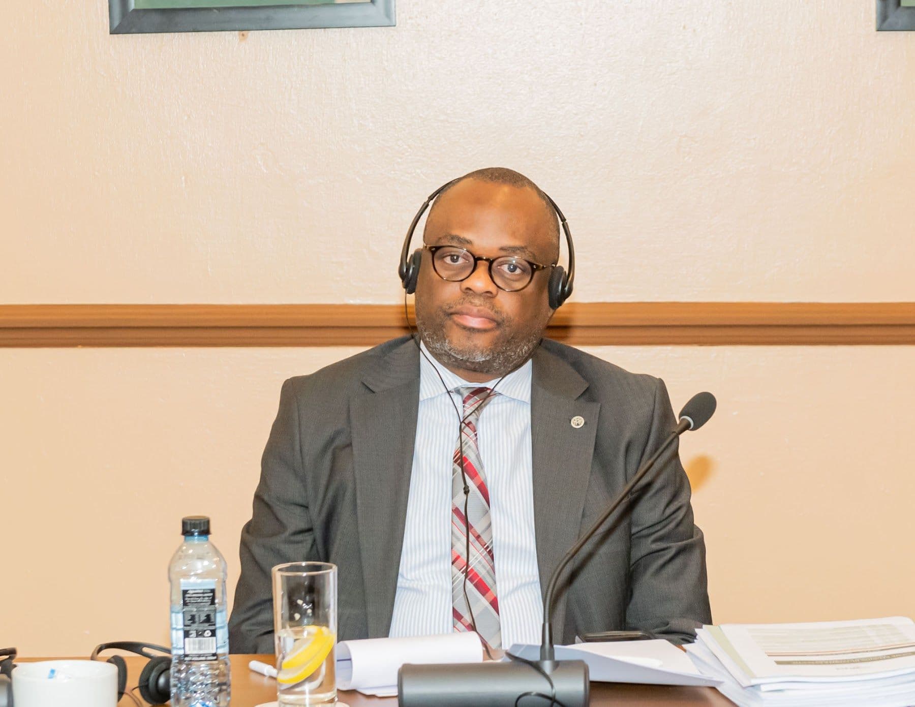A delegate at the meeting table with a microphone and a stack of meeting papers.