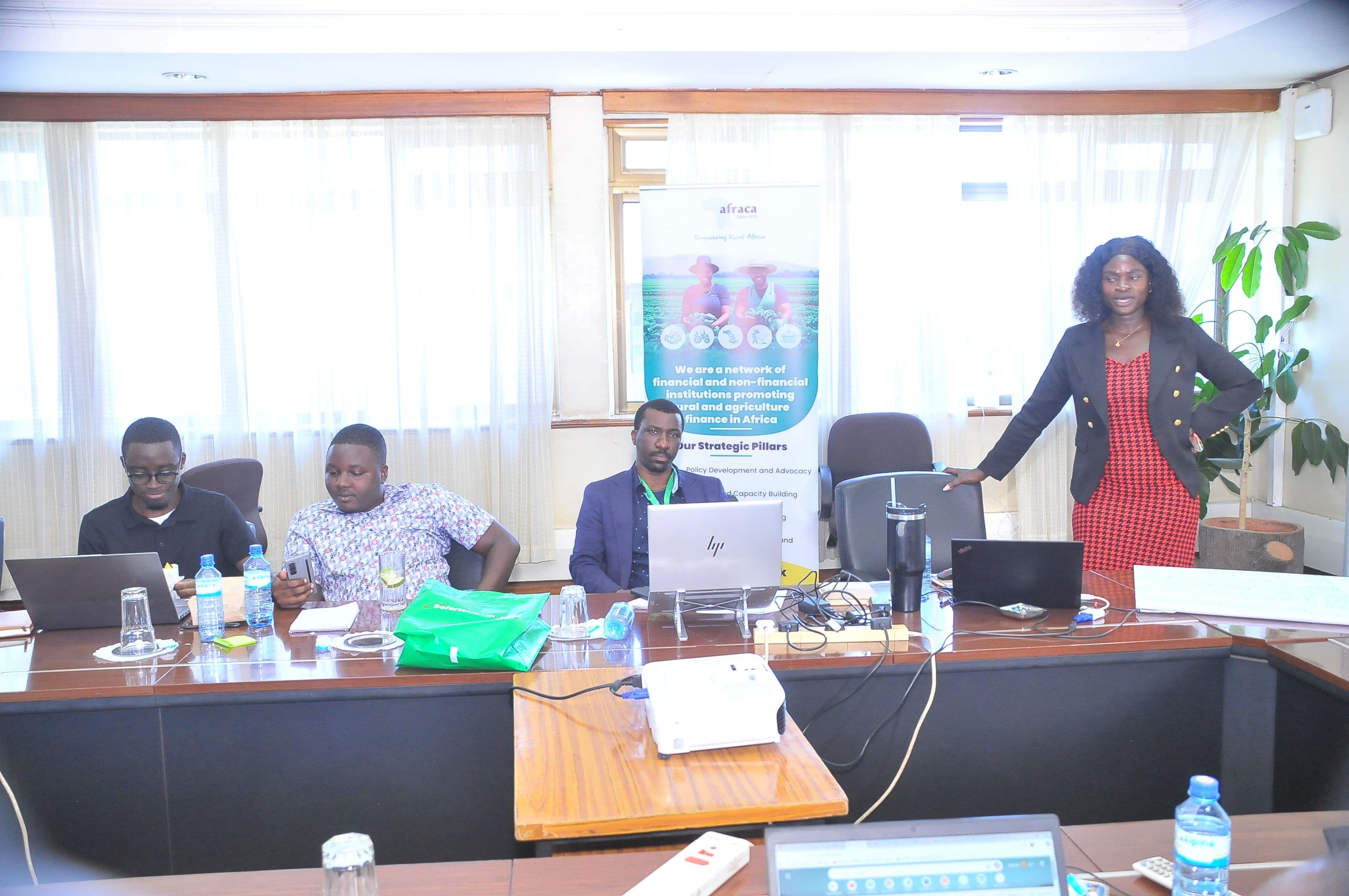 A facilitator presents beside an AFRACA banner while participants follow on laptops.